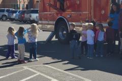 Children in school uniforms gathered around fire truck — fire prevention 2020