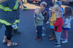 Adult in safety vest instructing children — fire prevention October 2024