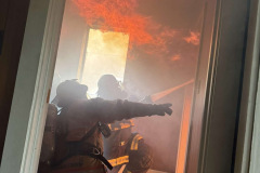 Silhouetted figure in tactical gear through window — training burn July 2025