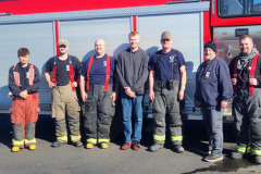 Firefighters and personnel in line in front of truck — fire prevention October 2024