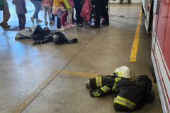 Firefighter demonstrating gear on ground — fire prevention 2025