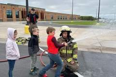 Firefighters in full gear interacting with children — fire prevention 2023