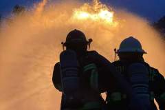 Two firefighters in silhouette spraying water — propane emergency training 2023