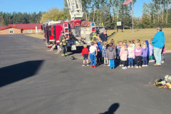 Children and adults in line next to fire truck — fire prevention October 2024