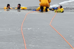 Multiple people in water wearing yellow safety gear — ice rescue training 2023