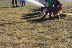 Group operating fire hose on grass — fire prevention October 2024