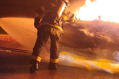 Firefighter spraying water on fire — propane burn training November 2025