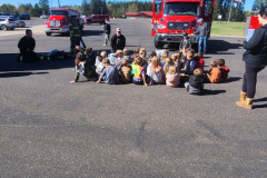 Children in safety vests gathered in semi-circle — fire prevention 2025