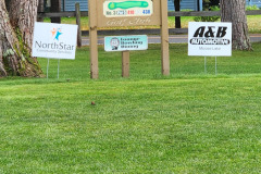 Business sponsor signs on lawn — golf scramble fundraiser September 2025
