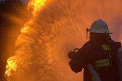 Firefighter from behind directing hose — propane emergency training 2023