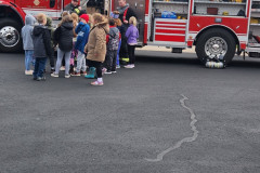 Children and adults gathered around red fire truck — fire prevention 2023